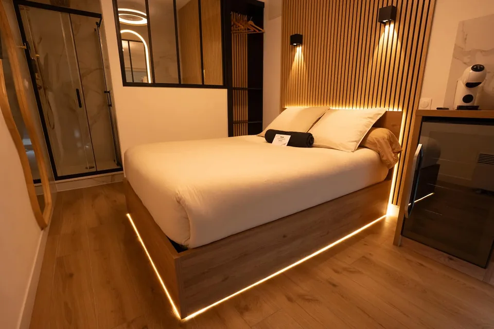 Vue d'ensemble du lit double, de la tête de lit en bois et de la salle d'eau
