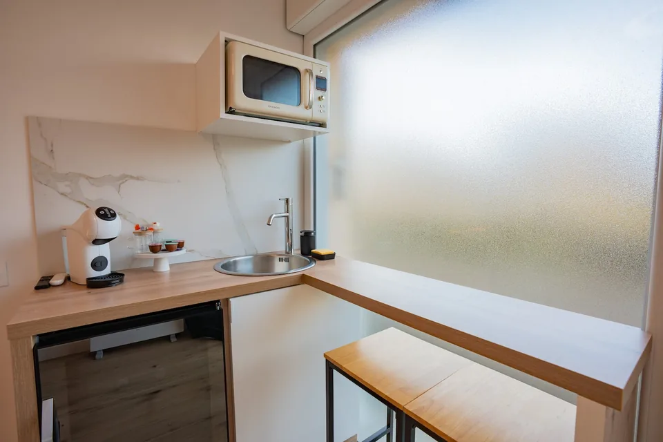 La kitchenette avec évier, machine à café, micro-ondes et réfrigérateur